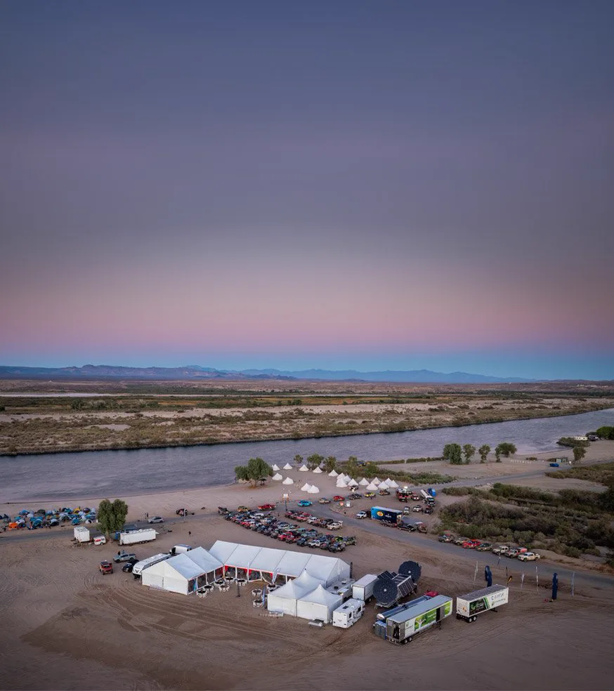 Aerial view at dusk of the Rebelle Rally desert base camp, with Renewable Innovations hydrogen systems parked beside the tents